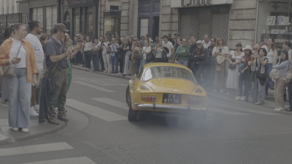 Crowd watching a yellow classic car straight out of camera in flat Apple Log