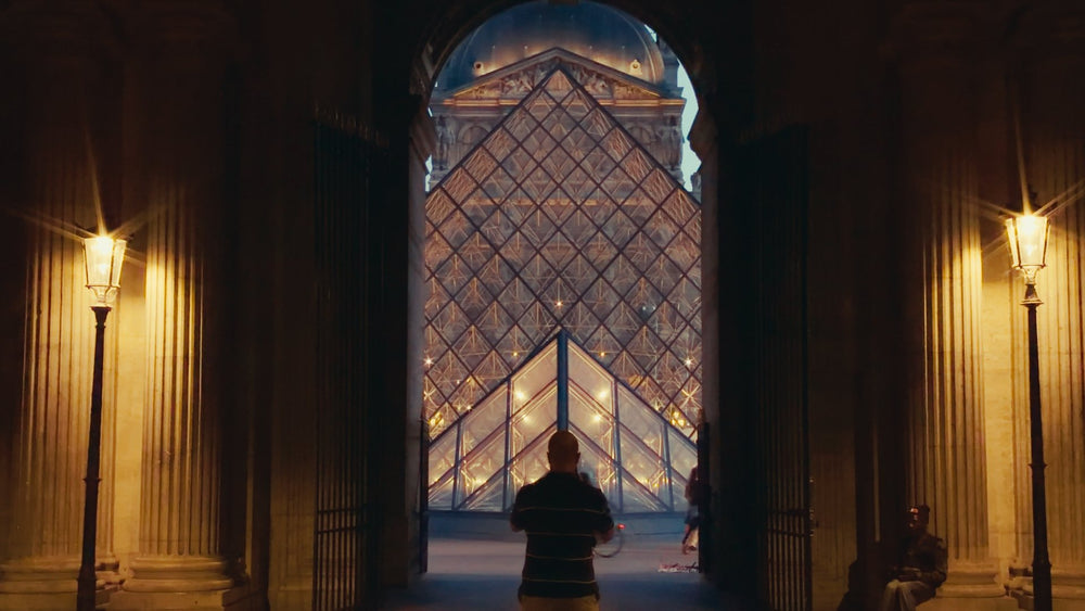 The Louvre pyramid framed by an archway at night graded with Ypresets Apple Log LUT 18